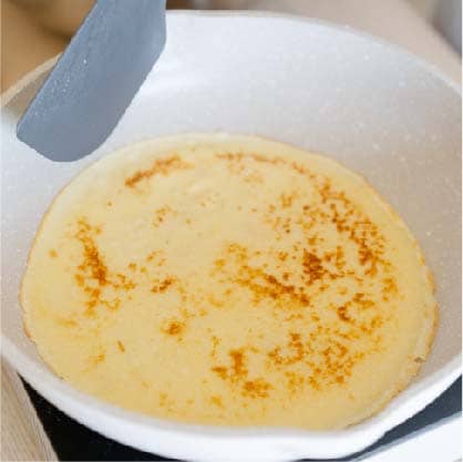 熱鍋後抹上薄薄的奶油，倒入一勺麵糊，煎至表層凝固後翻面。
