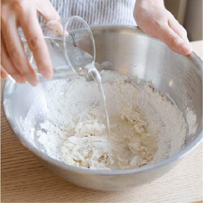 將高筋麵粉、玉米粉、鹽巴放入盆中拌勻，分次加入水攪拌，再加入蔥花。