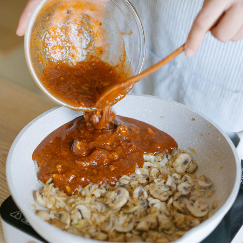 將洋蔥末和切片蘑菇放入鍋中炒熟，再倒入義大利肉醬拌炒後，放入莫札瑞拉起司以小火煮至融化。