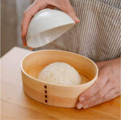 將白飯塑形成圓後,倒蓋至餐盒中。