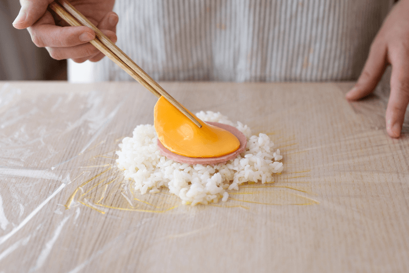 將白飯與味醂拌勻後包入剪裁成圓形的新東陽三明治火腿和起司。