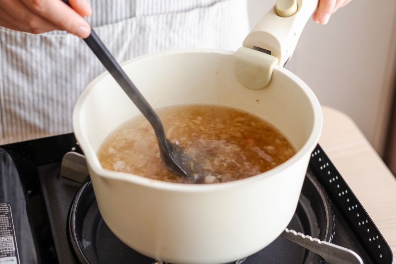 爆香油蔥酥和香腸末,加入鹽、糖、水和高湯包拌勻。 取出高湯包後,倒入玉米粉拌煮均勻。