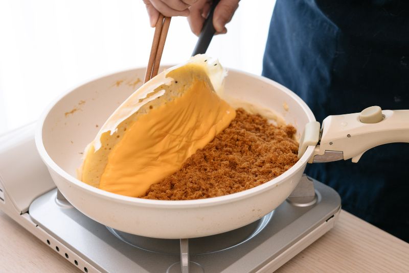 小火慢煎約10分鐘至浮出氣孔後，開蓋放入肉鬆和起司/美乃滋繼續悶煎3分鐘。