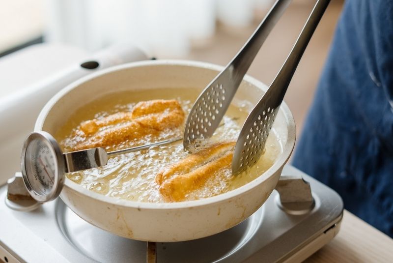 取出麵團後待恢復常溫，橫切對分後切作寬3公分的小塊，並 在中間壓印1刀。將麵團拉長，下鍋以190度油炸，過程中持 續轉動，直到表面金黃膨脹即可取起。