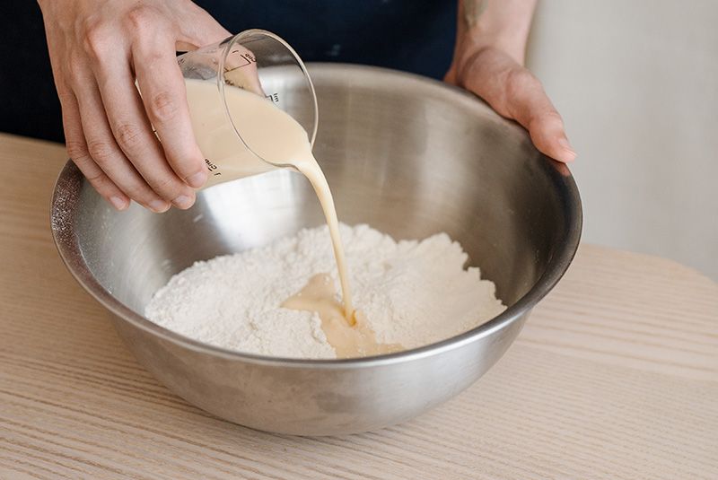 將中筋麵粉、泡打粉、小蘇打和鹽混合均勻後，將雞蛋和常溫豆漿拌勻，再分3至4次拌入。