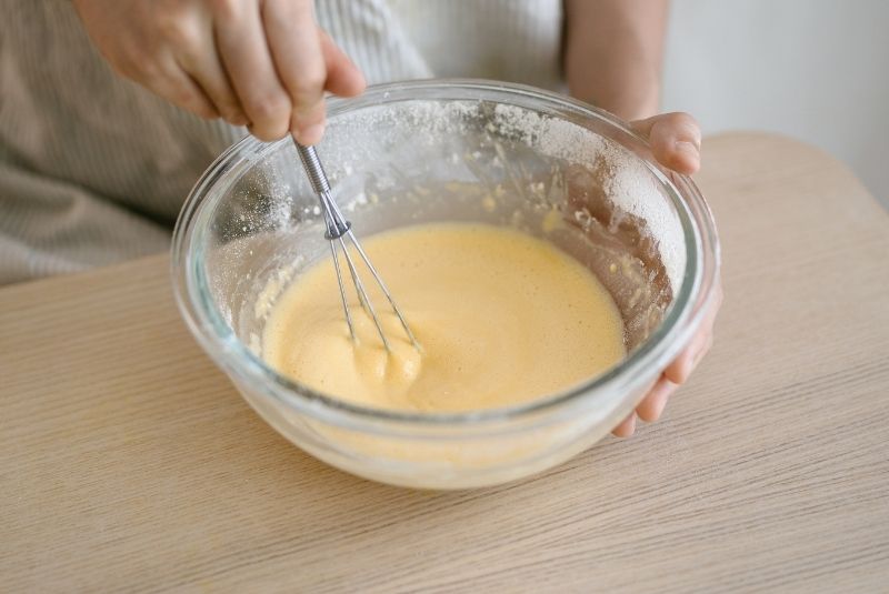 將牛奶和植物油隔熱水攪拌後，倒入蛋黃攪拌均勻，拌入過篩低筋麵粉。