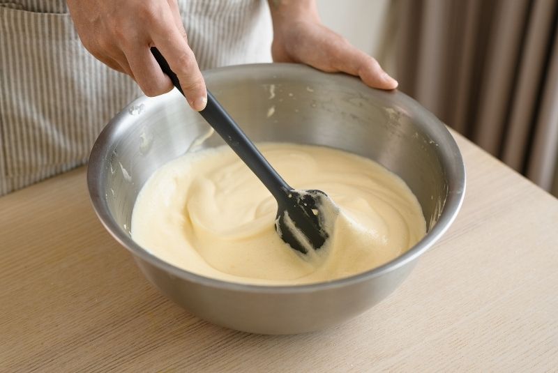 將1/3 蛋白霜拌入麵糊，再倒回主蛋白霜繼續翻拌。 提示 1：濕性發泡會呈現白色綿密泡沫狀並掀起彎鉤，硬性發泡則會呈現立體，拉出硬挺的尖鉤。 提示 2：以翻拌的方式，麵糊才不會筋化。