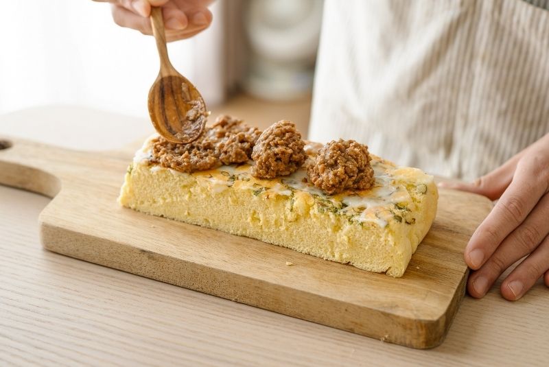 脫模後對半切，取蔥面作為下層，抹勻美乃滋後鋪放新東陽台灣黑豬滷肉。